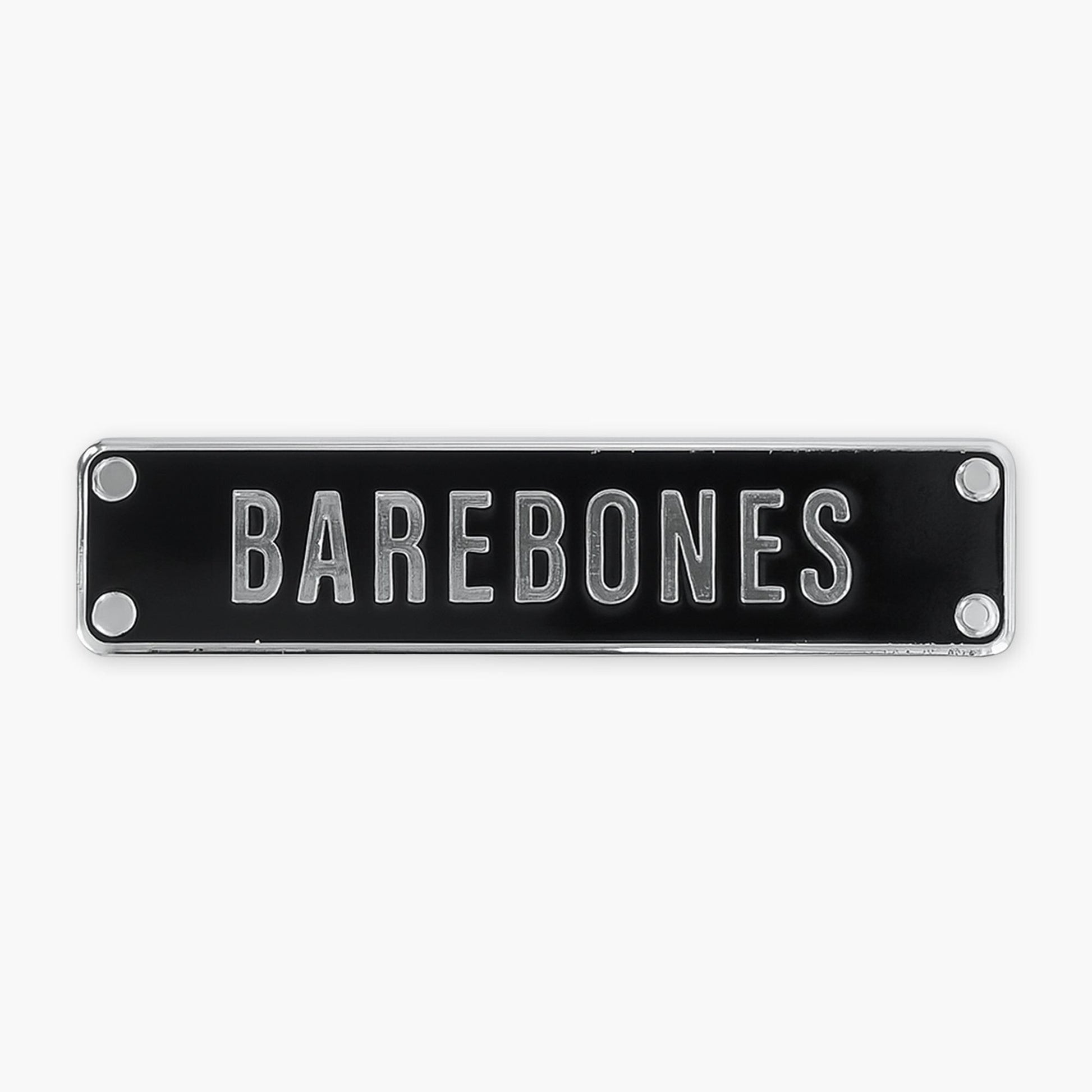 Enamel pin of a black rectangular sign with 'BAREBONES' text on a white background