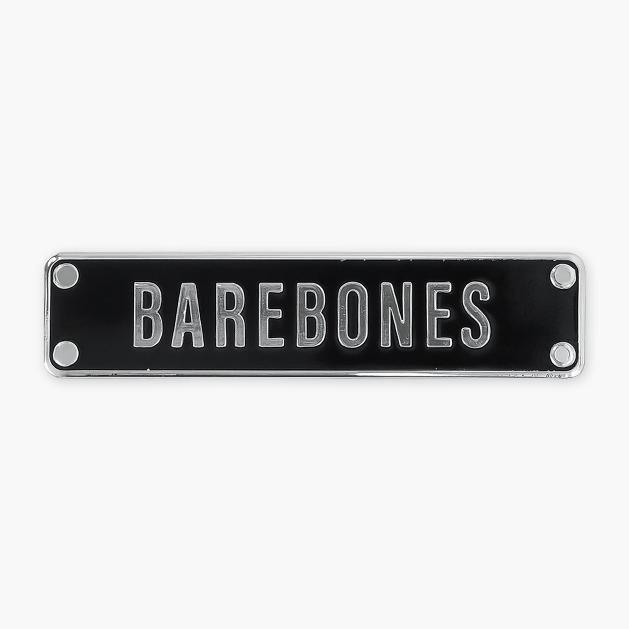 Enamel pin of a black rectangular sign with 'BAREBONES' text on a white background